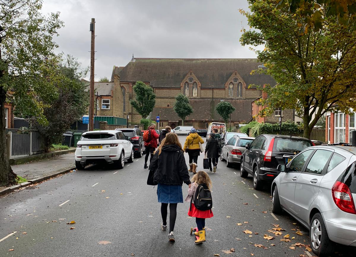 Children walking to school in the middle of a road